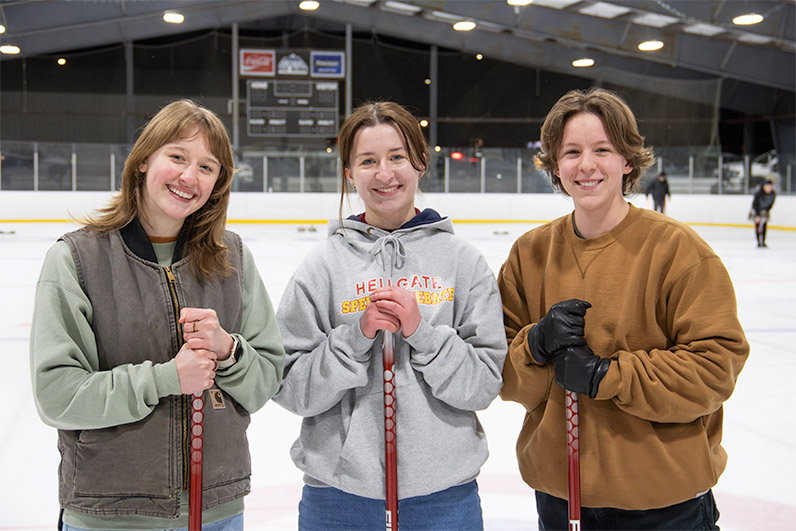 Three Curlers standing on the ice and smiling at the camera